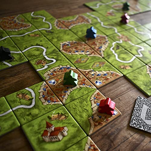 Losetas del juego de mesa Carcassonne con diseños de ciudades, caminos y campos